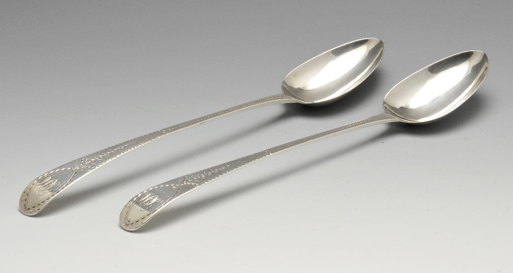 A pair of George III silver basting spoons in Old English pattern, each stem with bright-cut