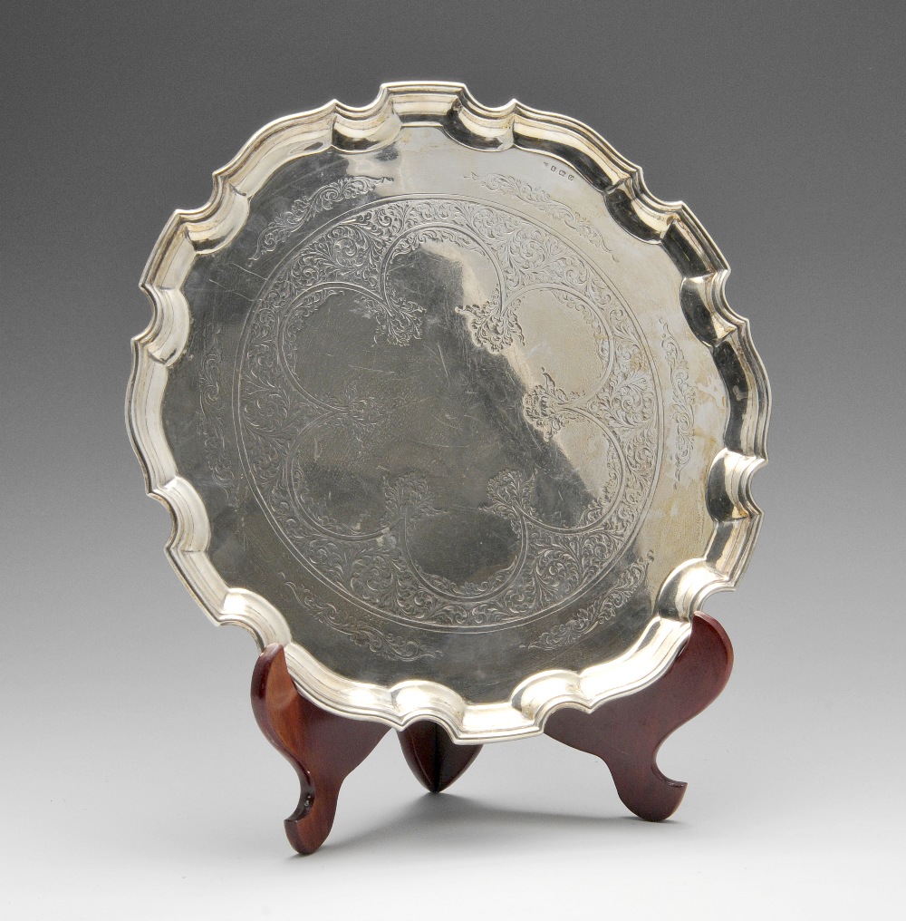 A 1920's silver salver, decorated with a lobed foliate scrollwork panel to centre within a raised