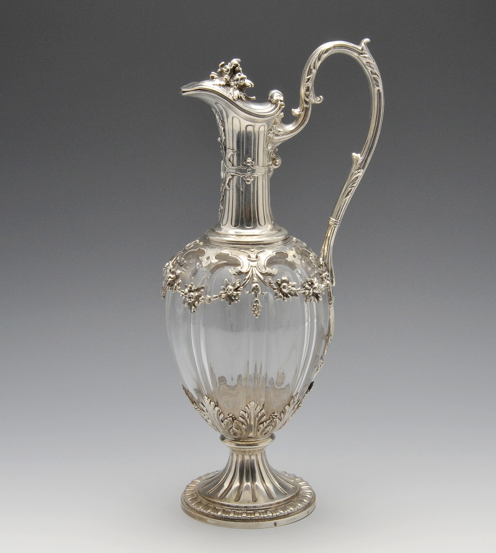 A French silver mounted claret jug, the segmented body overlaid with floral swags rising to the