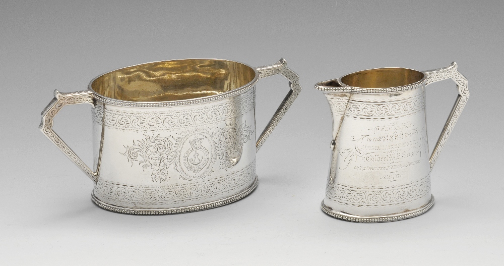 A Victorian silver sugar and cream with military interest, the oval tapered bodies within beaded