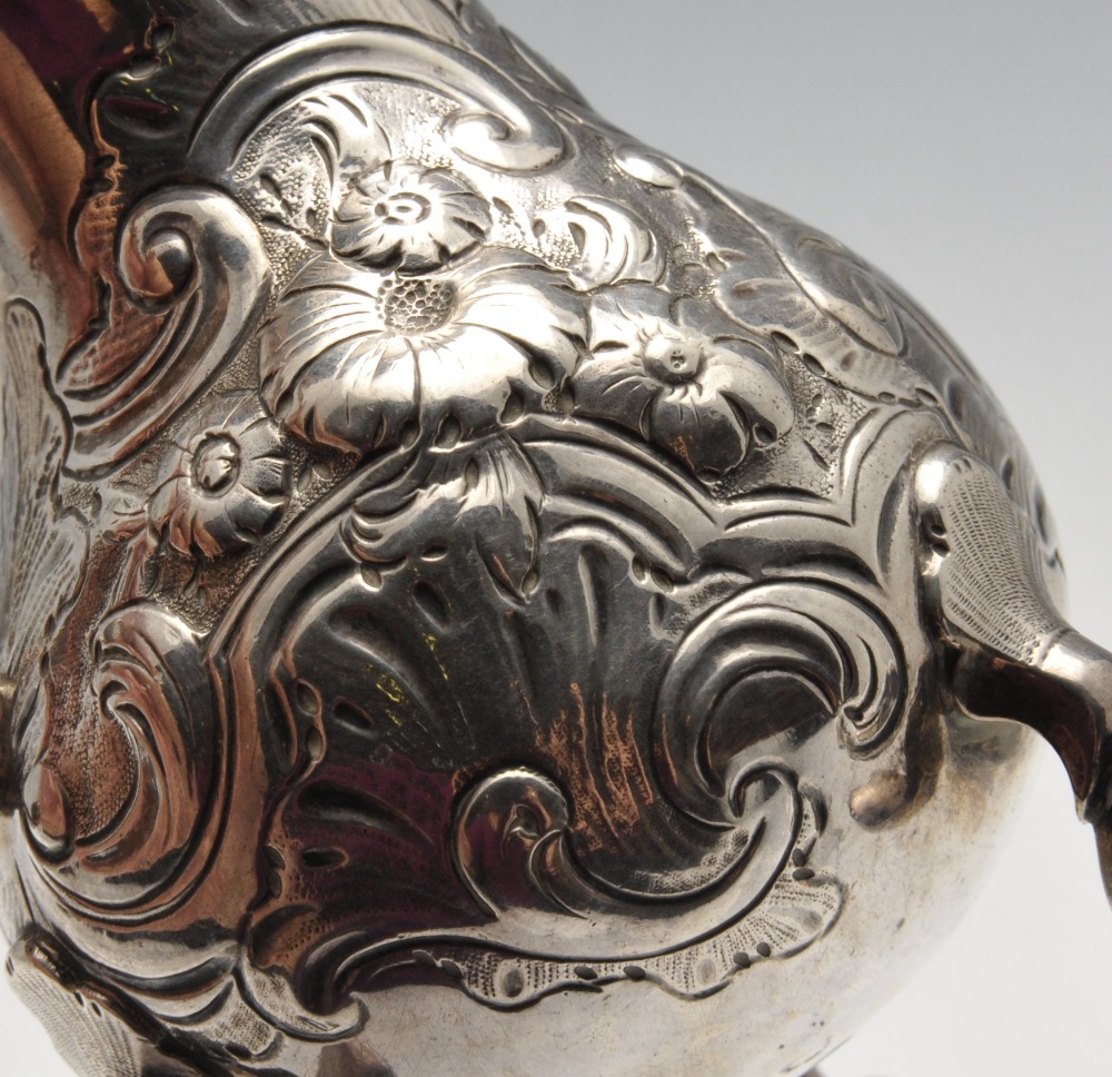 A George II silver cream jug of bulbous form with floral embossing surrounding an engraved crest, - Image 3 of 4