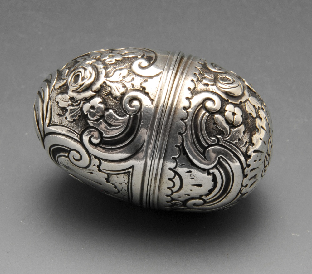 An eighteenth century nutmeg grater, the ovoid form with floral and scroll embossed decoration.