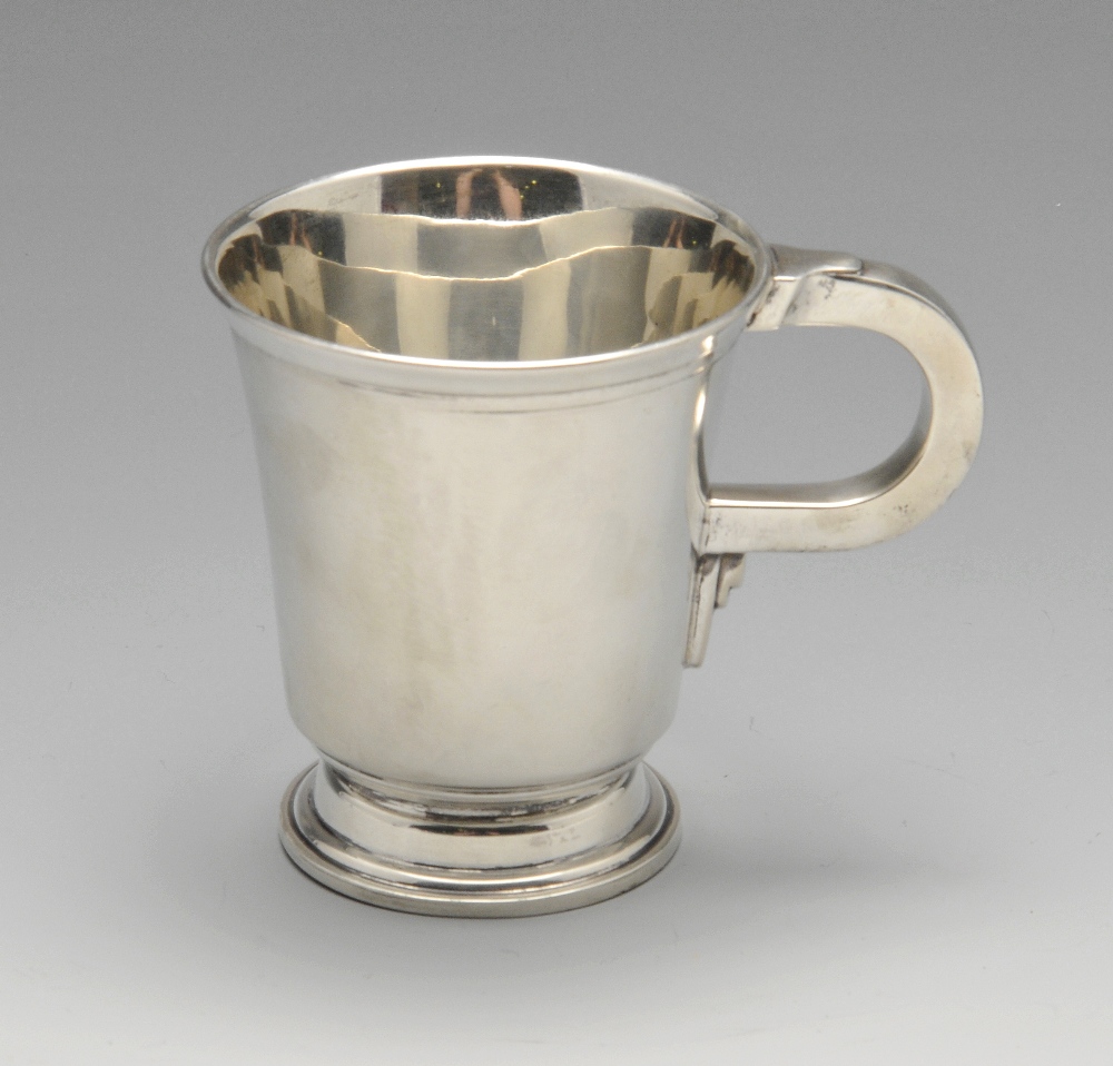 An Art Deco silver mug, of slight tapered form having accented handle raised upon a stepped foot.