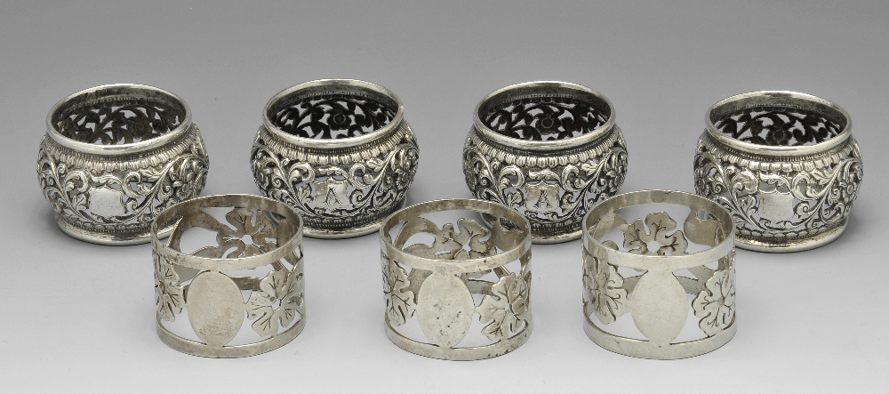 A set of three silver napkin rings of pierced circular form and decorated with stylised floral