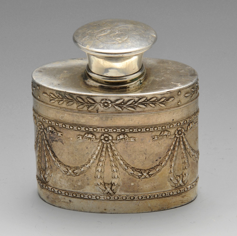 An early twentieth century silver tea caddy of oval form, decorated with a trailing leaf border