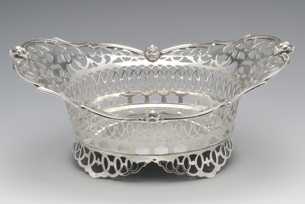 An Edwardian silver bread basket, the oval pierced openwork body with scroll and mask rim and raised