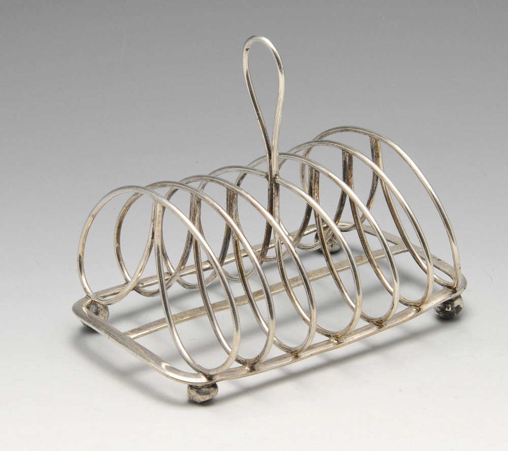 A George IV six-divide silver toast rack, the kidney wirework frame on oblong base and raised on