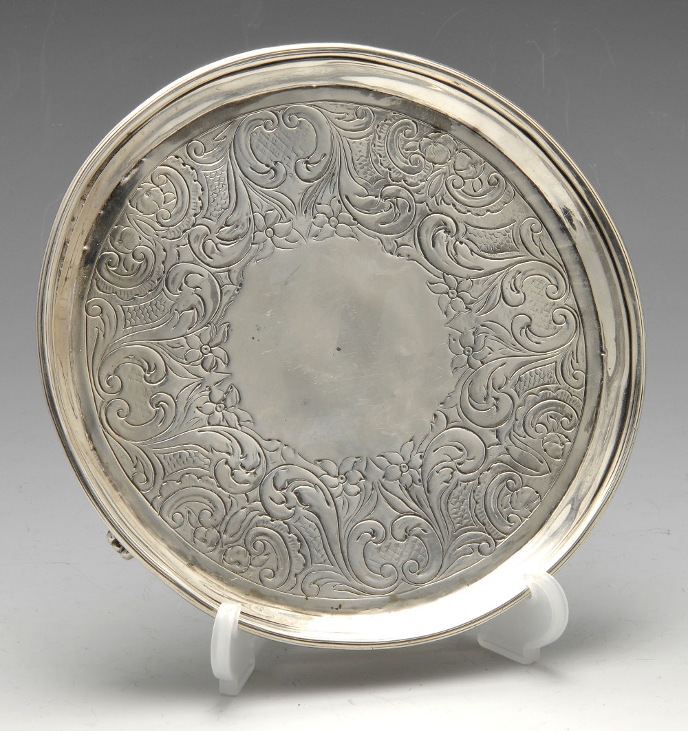 A George III silver waiter, the circular form with floral scroll surround to the vacant cartouche