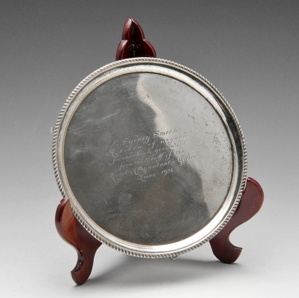 A 1920's small silver salver of circular form with oblique gadrooning to rim and raised on three