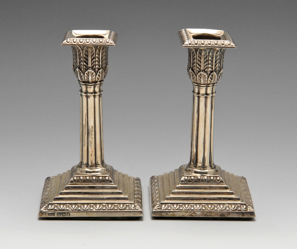 A pair of late Victorian silver candlesticks, each with loaded and stepped square base having