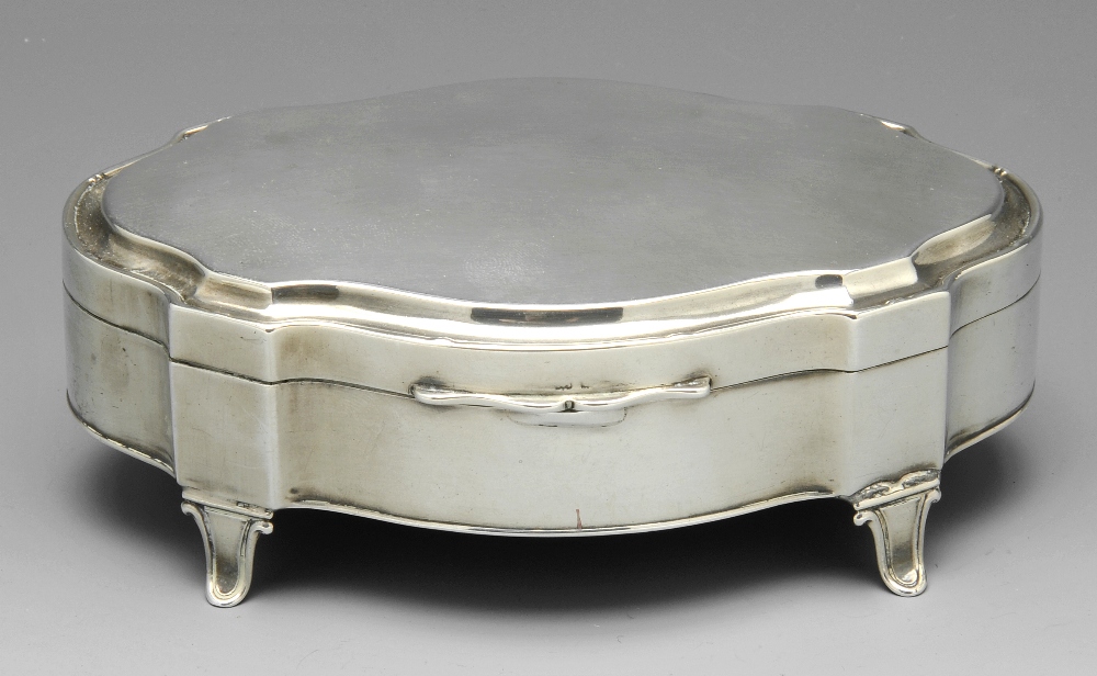 An early twentieth century silver mounted trinket box of shaped oval outline and raised on four