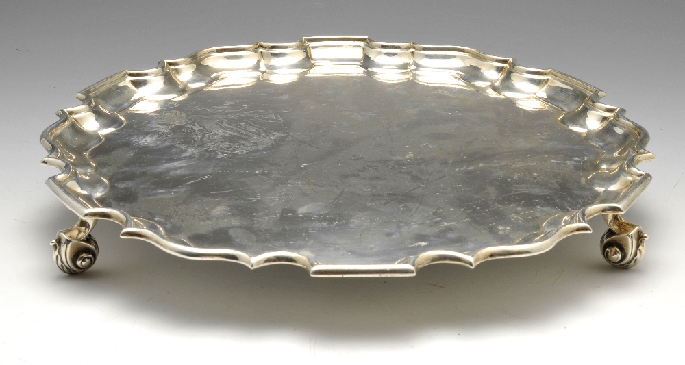 An early twentieth century silver salver, the circular body with Chippendale style rim and raised on