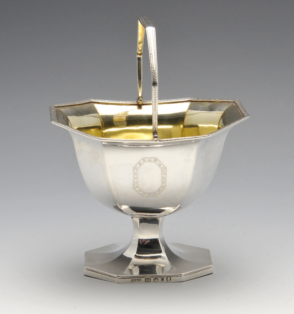 A George III silver swing handle sugar basket, the octagonal sided pedestal form having twin opposed