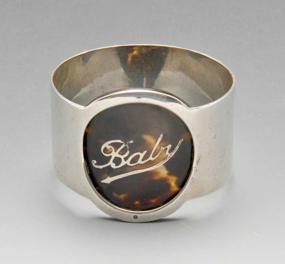 An Edwardian silver single napkin ring, the plain circular form with applied tortoiseshell panel