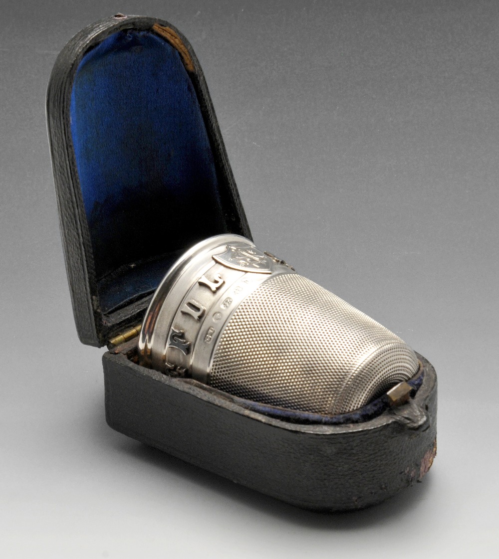 A cased Victorian silver novelty shot cup modelled as a thimble, with raised lettering 'Just a