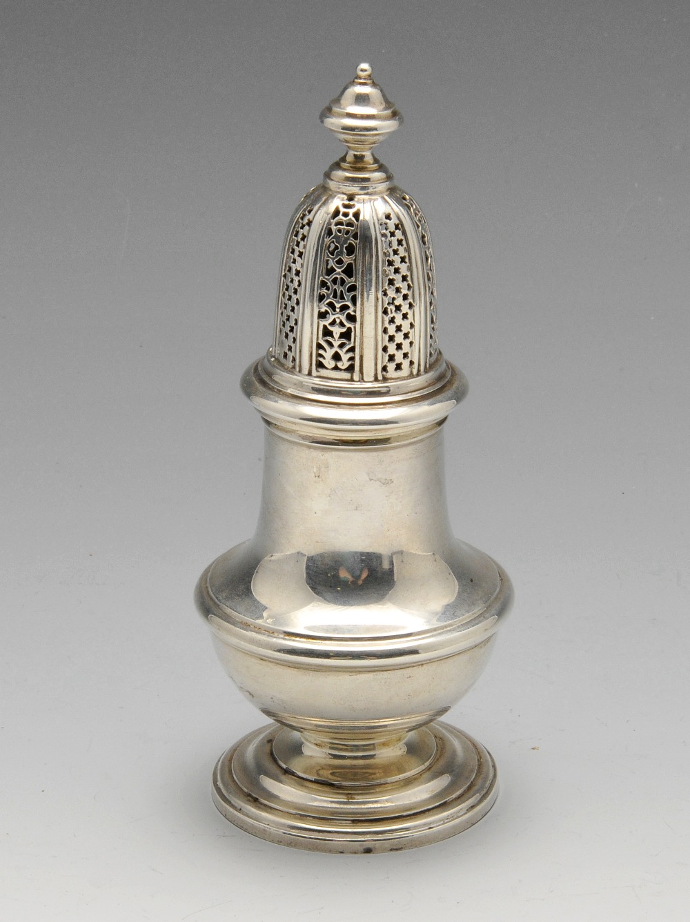 A modern silver caster in Georgian style, the vase shaped body with embossed girdle, raised on a