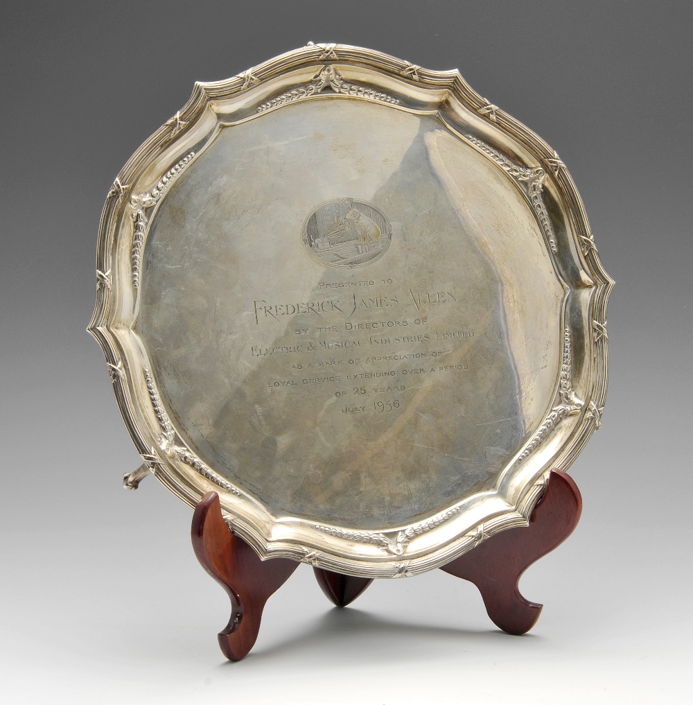 A 1930's silver salver of shaped circular outline, having a ribbon and reed rim enclosing a border