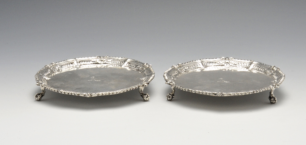 A matched pair of George III silver waiters, the circular form with central crest, raised shell