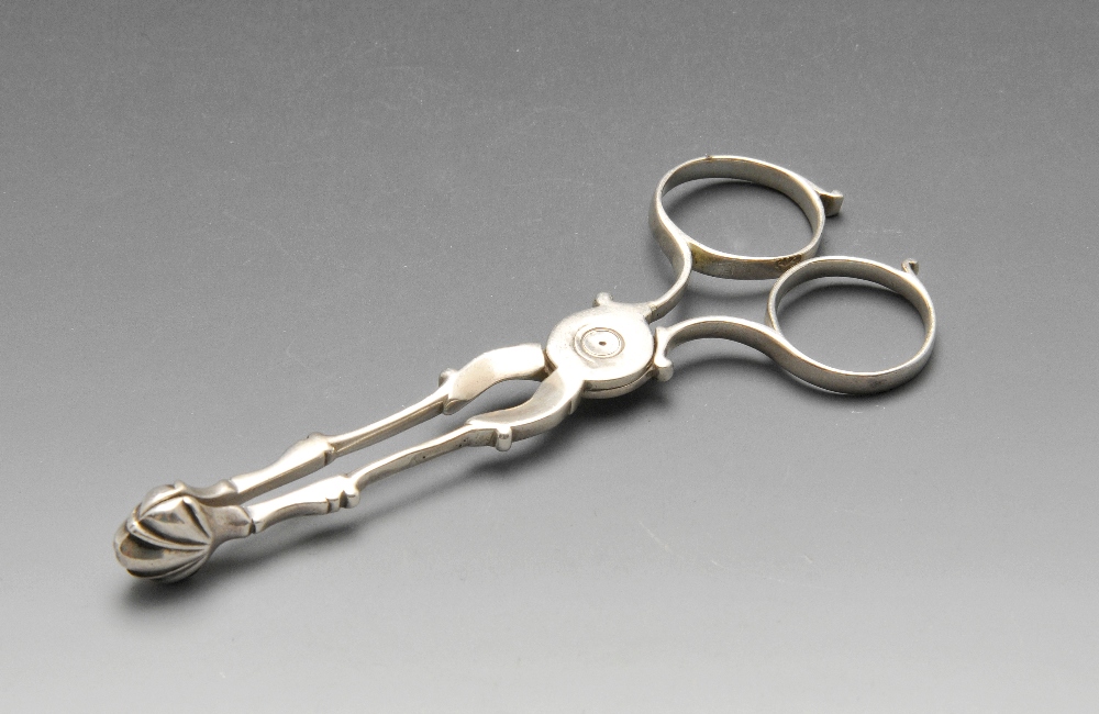 A pair of Georgian silver scissor action sugar tongs with circular loop handles and scroll arms
