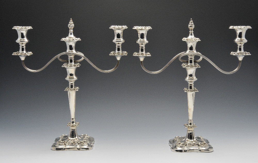 A modern pair of silver twin branch candelabra, each with shaped square base rising to a knopped,