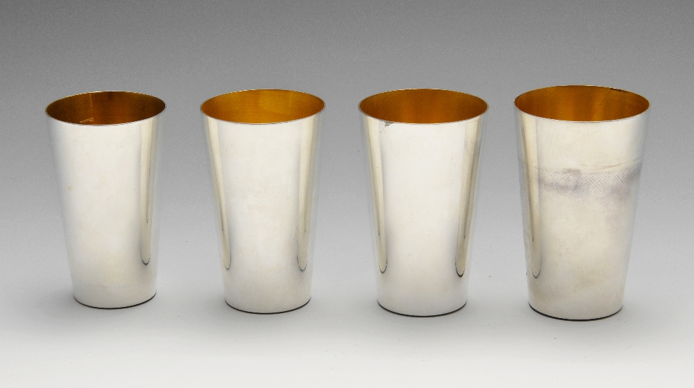 A set of four modern graduated silver beakers, of plain tapering cylindrical form having gilt