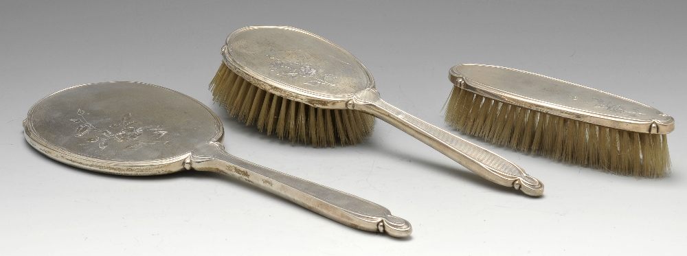 A 1950's silver three piece dressing table set comprising hand mirror, hairbrush and clothes