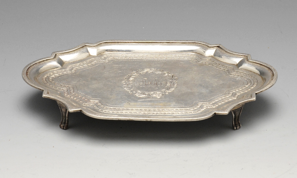 A George III silver teapot stand of scalloped navette form with central monogram within floral
