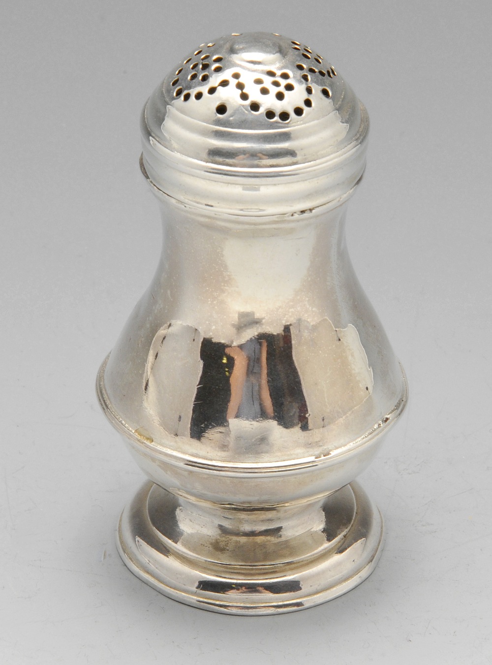 A George II small silver caster, the plain baluster form with girdle detail and raised on a footed