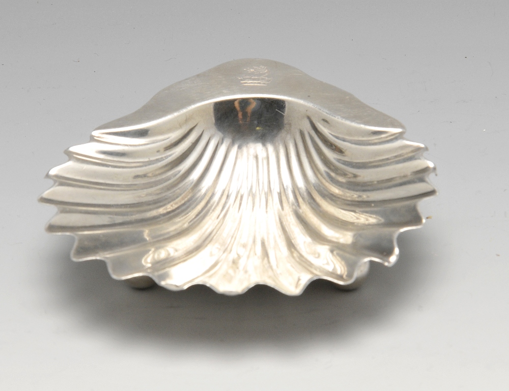 An early twentieth century silver butter shell of classic form, crested and raised on three ball