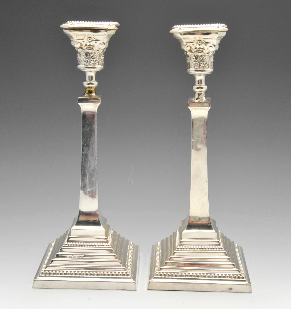 A pair of mid-twentieth century silver candlesticks, each with a stepped square base having beaded