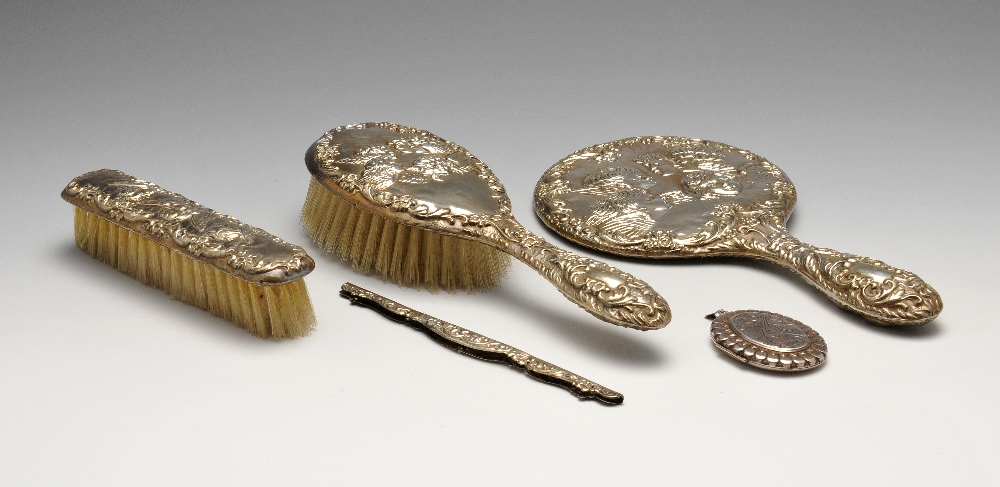 A 1970's silver mounted part dressing set having embossed cherub decoration within floral scrolls,