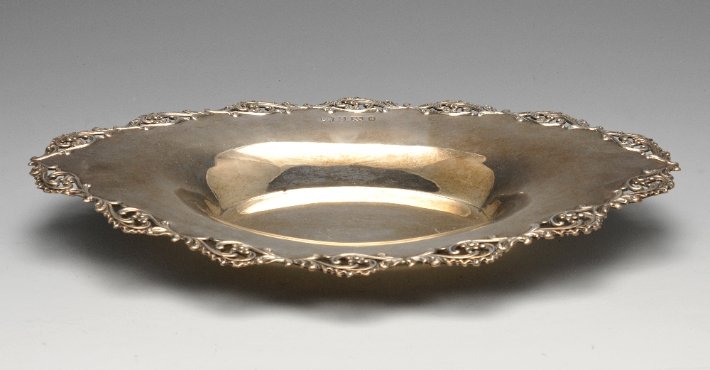 An Edwardian silver dish of oval outline having pierced foliate border to the wide flaring rim,