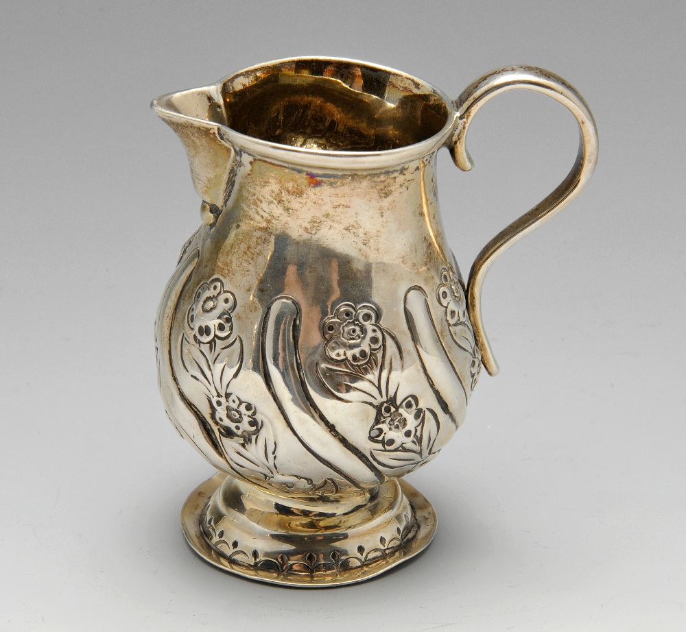 A George III silver cream jug, the bellied form with oblique and floral embossing and sparrow