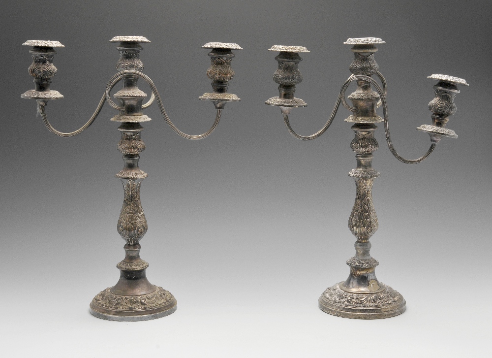 A pair of silver plated twin branch candelabra, each with a circular weighted base rising to a