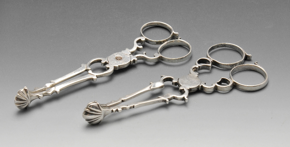 Two similar Georgian silver scissor action sugar tongs, with scroll arms and shell bowls. Part