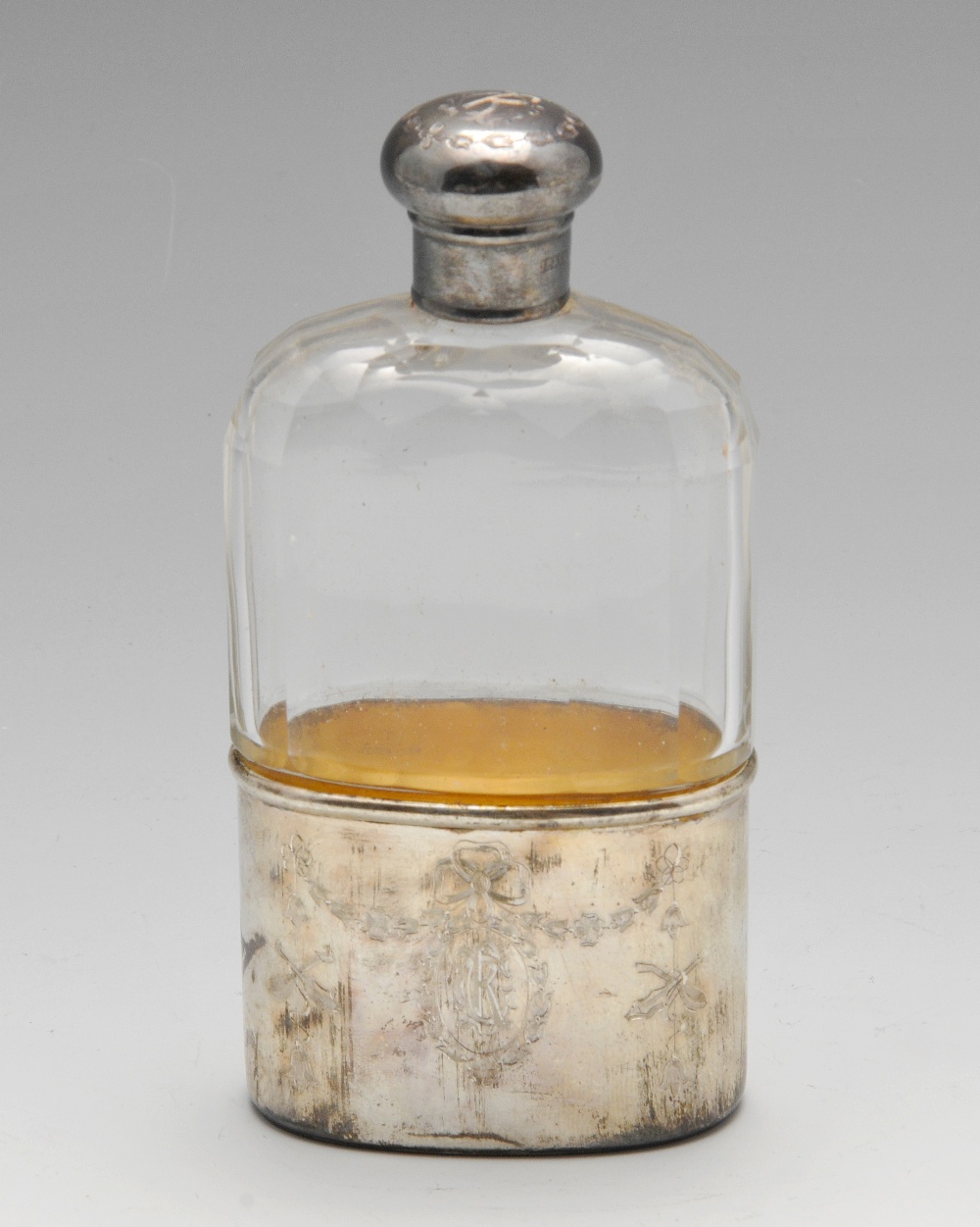 An Edwardian silver mounted hip flask, the clear glass body with faceted shoulders, the detachable