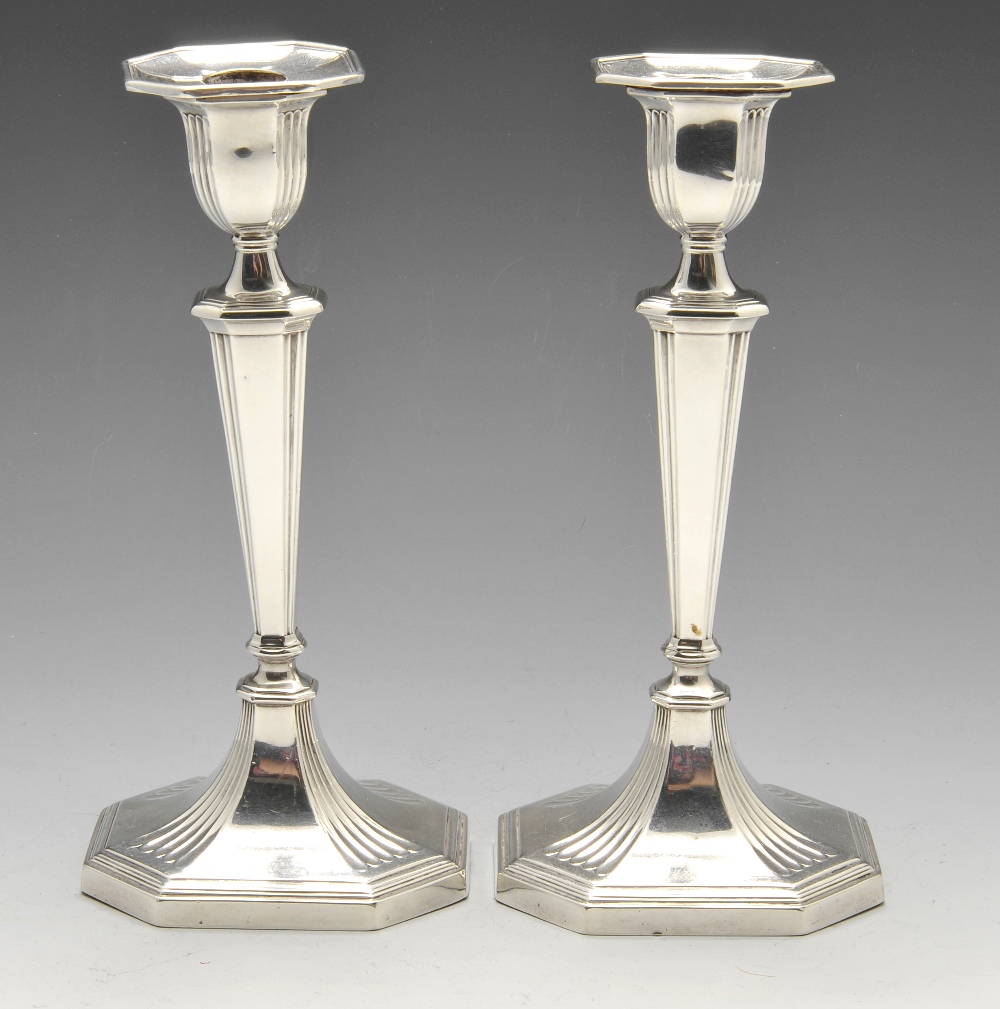 A pair of Edwardian silver candlesticks, each with octagonal sided loaded base rising to a