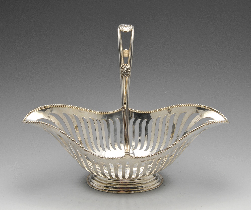 An Edwardian silver swing handle dish of elongated oval form with beaded rim above vertical