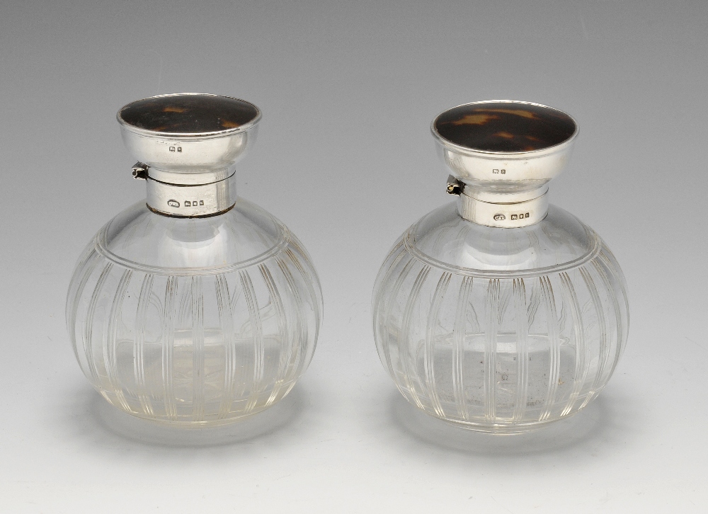 A pair of 1920's scent bottles, each with globular glass body rising to a plain silver collar and