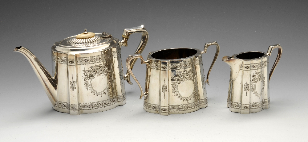 An Edwardian silver three piece tea service of tapering cornered oval form, bright-cut borders and