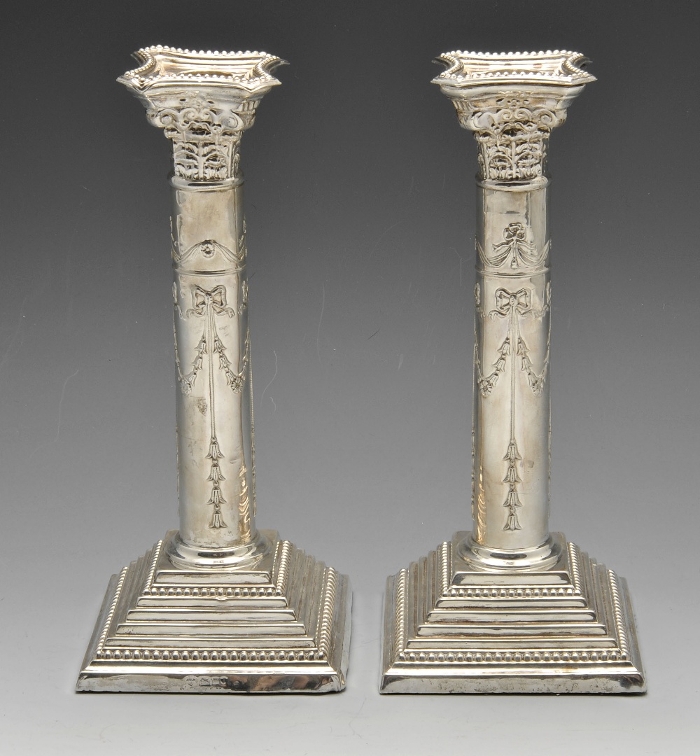 A pair of 1960's silver candlesticks, having raised garland swags tied with bows and pendant drops