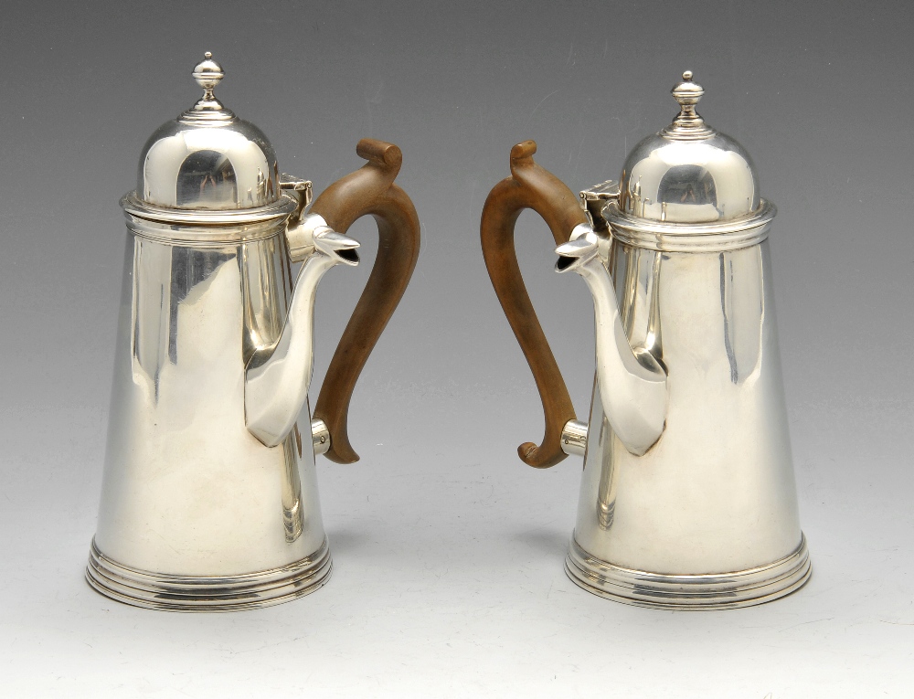 A pair of Edwardian silver chocolate pots of plain tapering form with domed hinged covers and