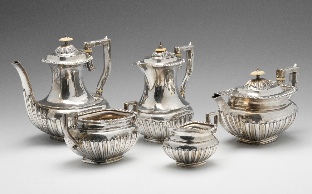 An Edwardian five piece silver tea service, of oblong form, the lower bodies fluted, rising to the