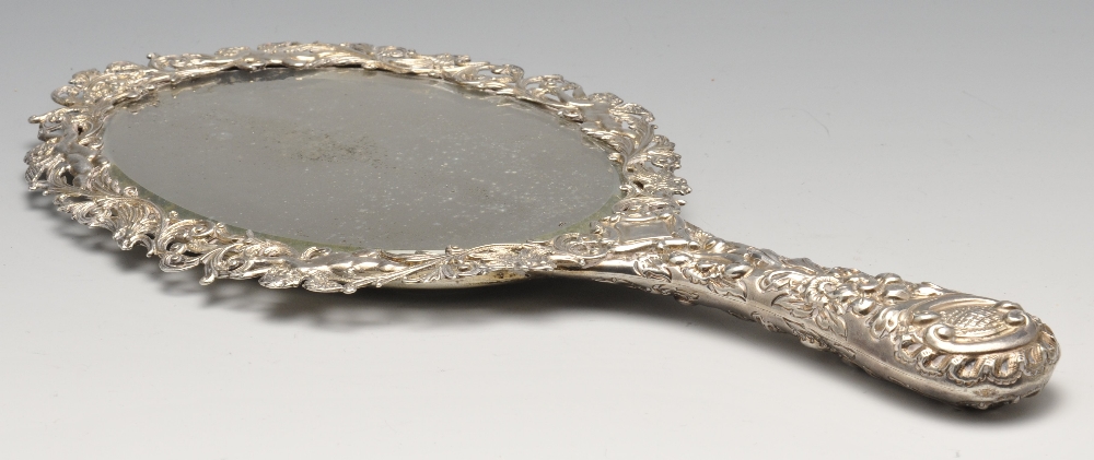 A late Victorian silver mounted hand mirror, the oval bevelled glass plate within an ornately - Image 2 of 8