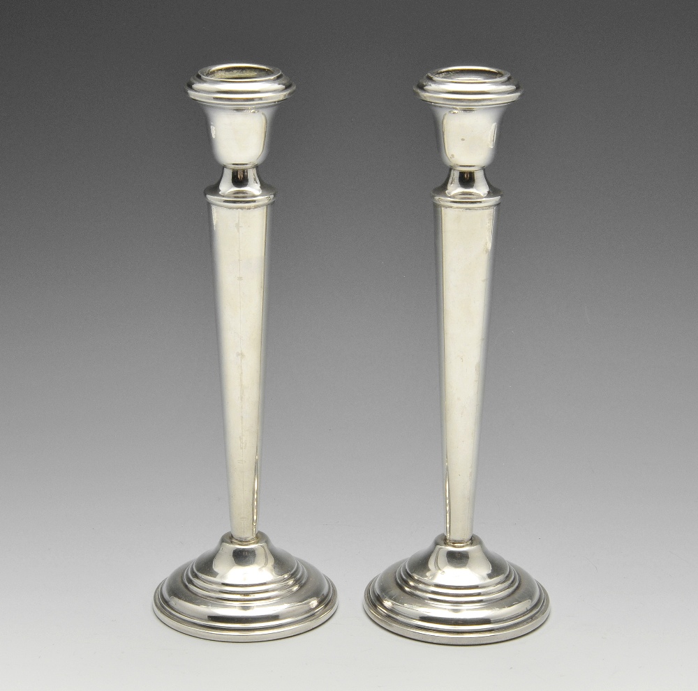 A pair of Egyptian silver candlesticks, the tapered columns raised on stepped circular bases and urn