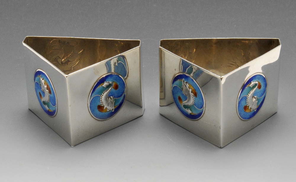 A pair of Edwardian silver napkin rings, each of triangular form and decorated with two blue and