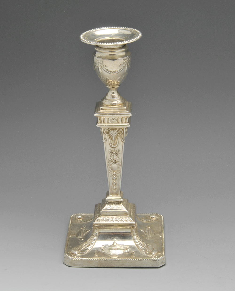 An Edwardian silver mounted candlestick of Neoclassical style, the urn shaped socket raised upon