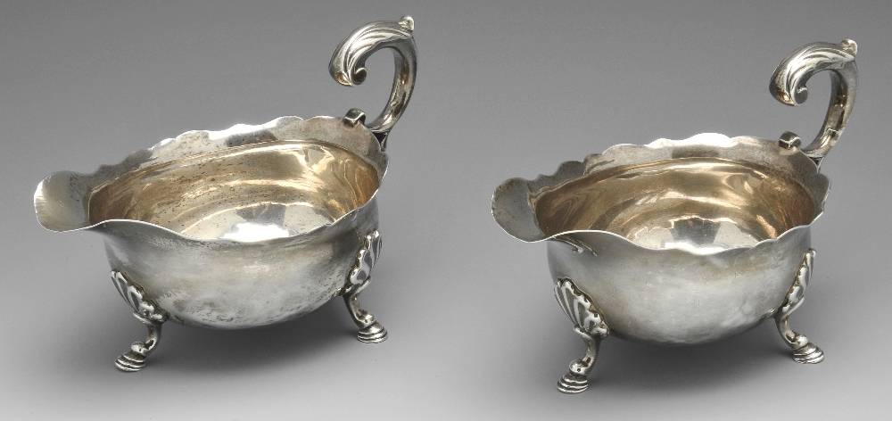 A pair of George II silver sauce boats, the oval bodies with scalloped rim, high arch leaf capped