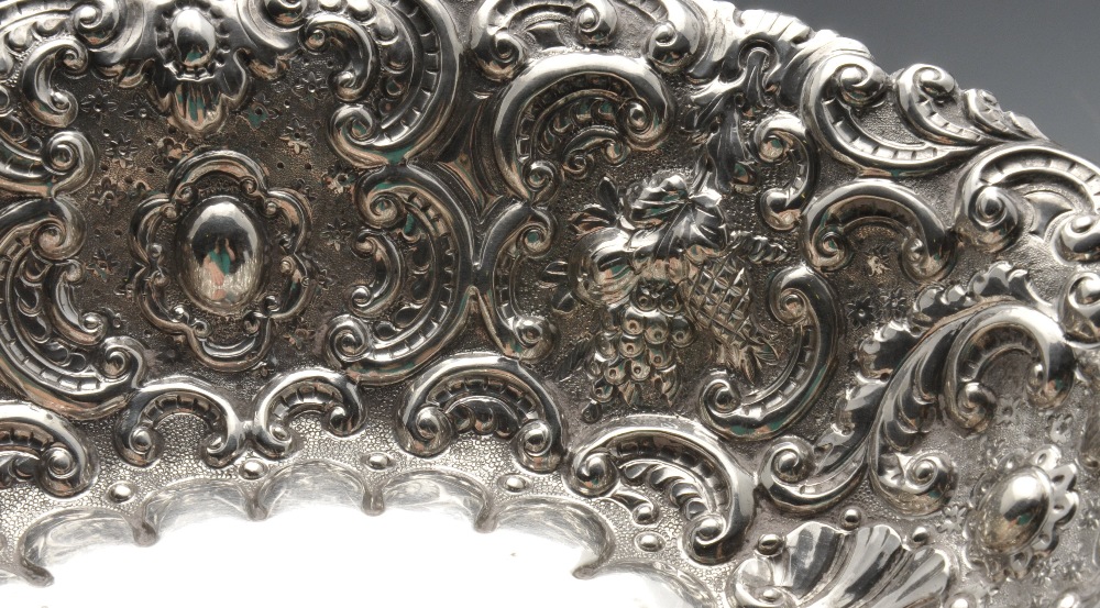 A Victorian silver dish of oval form, entirely embossed with fruiting and floral scrolls upon a - Image 4 of 4