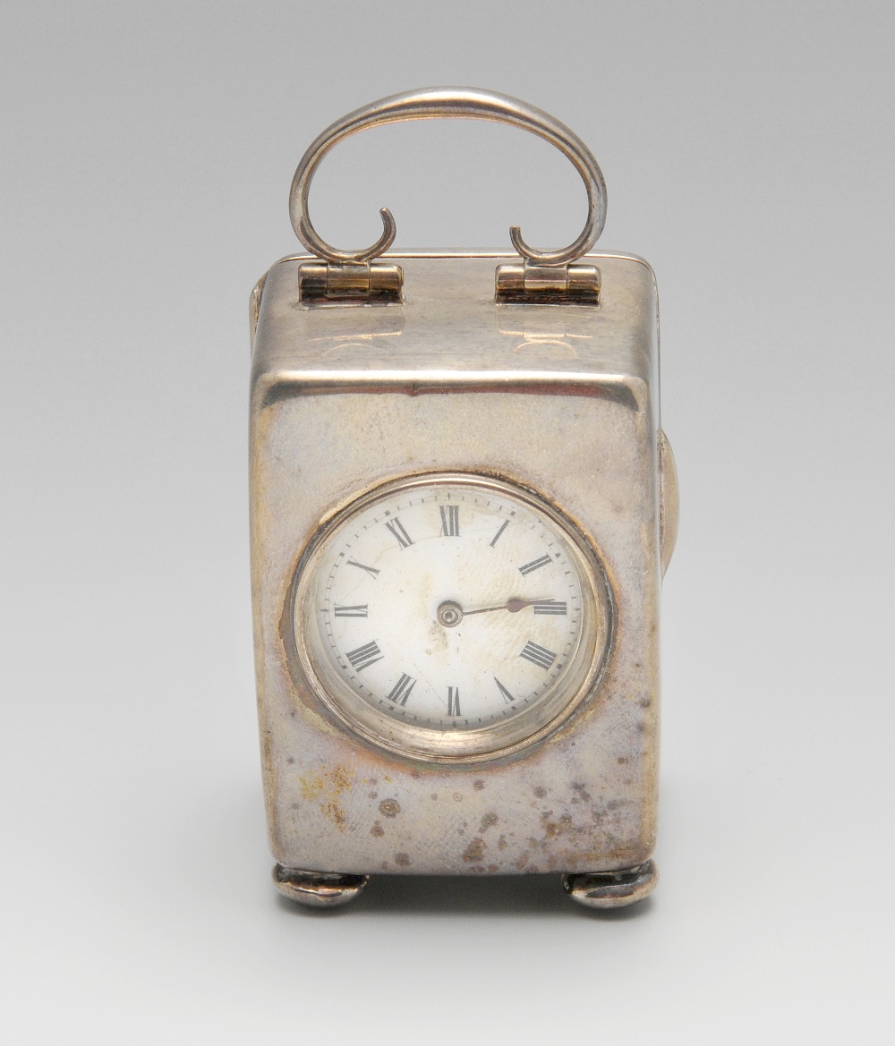 An Edwardian silver carriage clock, the plain oblong form standing on bun feet, circular aperture